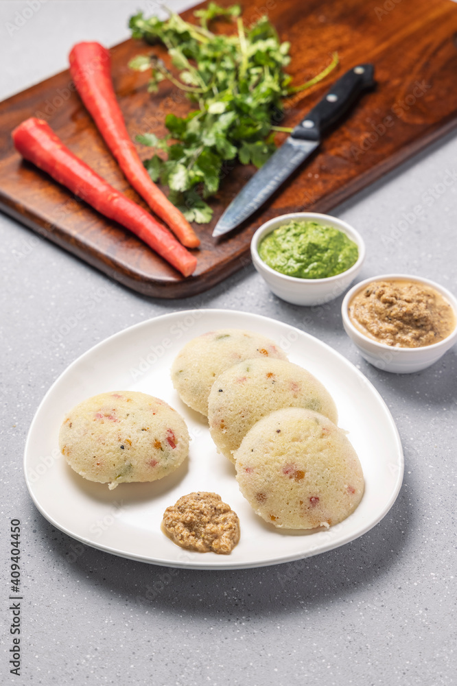 vegetable rawa idli served with coriander and coconut chutney with tomato sauce