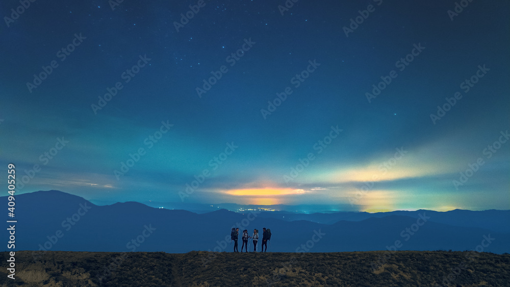 The group of hikers standing on the starry sky background