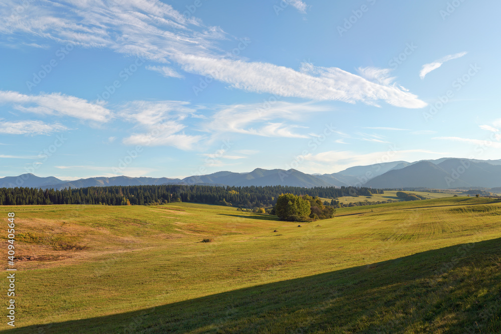 Autumn green meadows on small hills terrain, some mountains in background, typical landscape in Liptov region of Slovakia