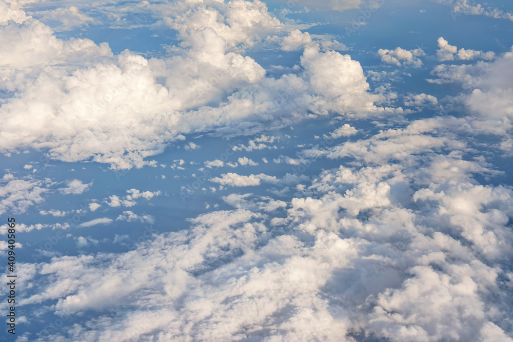 Fluffy sky clouds lit by afternoon sun, as seen from commercial airplane flying over Fluffy sky clouds lit by afternoon sun, as seen from commercial airplane flying over