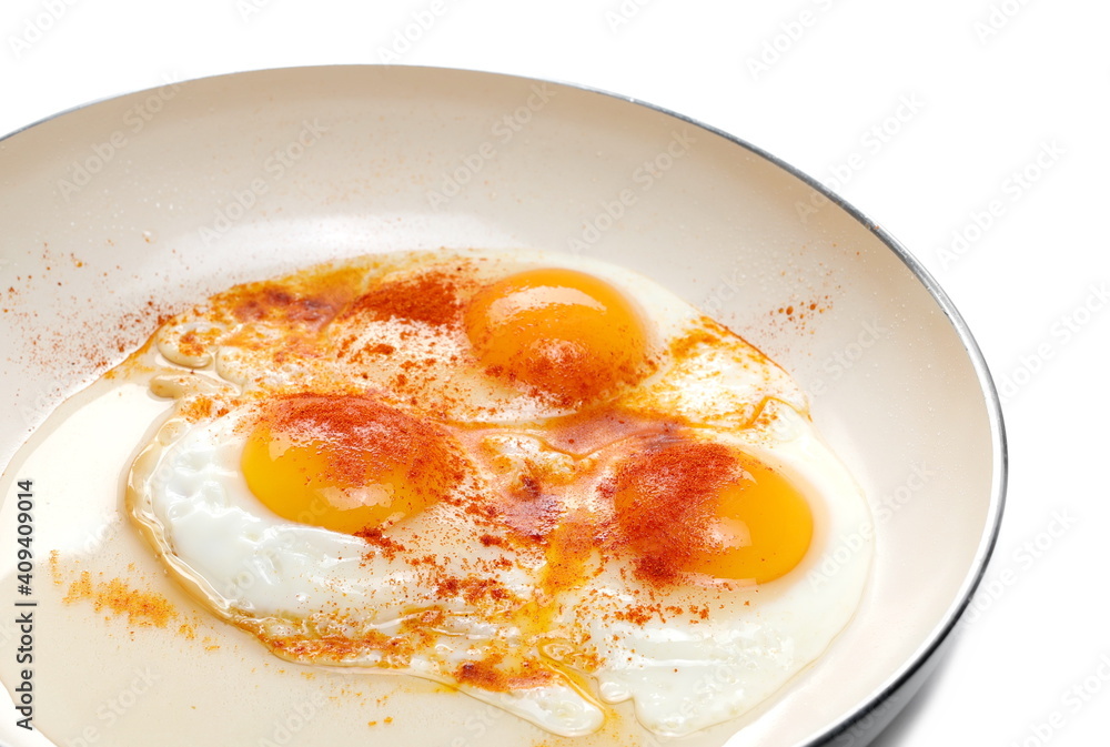 Fried eggs with ground paprika on frying pan isolated on white background Fried eggs with ground paprika on frying pan isolated on white background