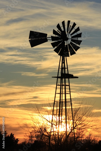 windmill at sunset with white clouds north of Hutchinson Kansas USA.