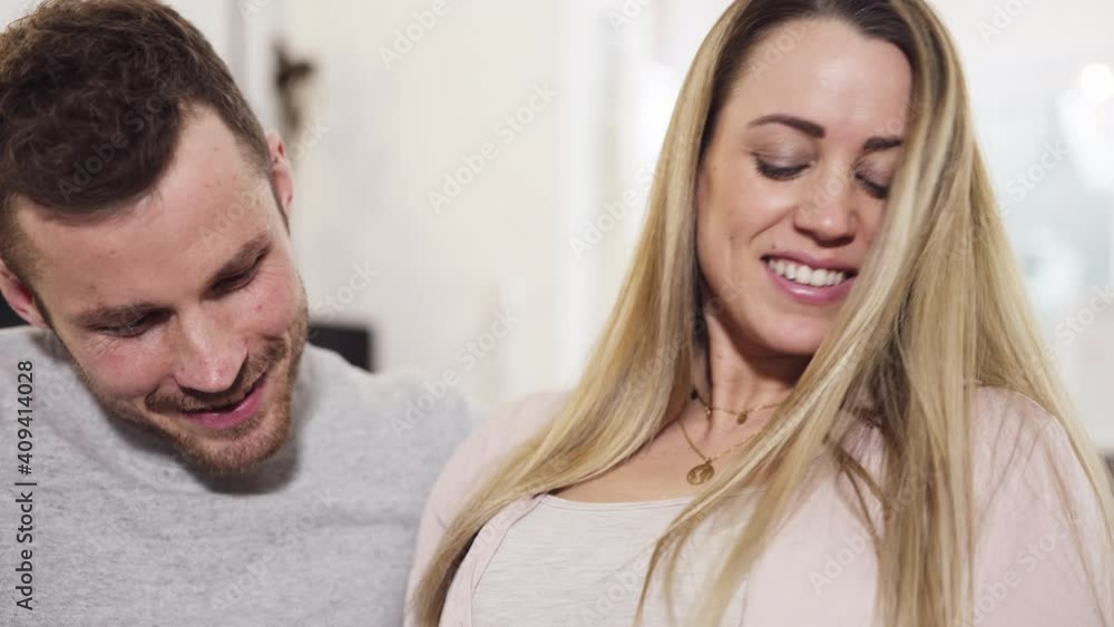 Close up of pregnant happy couple sitting on couch husband feels baby in belly of blond wife shot in 4k Close up of pregnant happy couple sitting on couch husband feels baby in belly of blond wife shot in 4k
