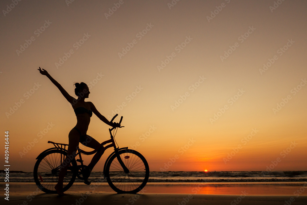 healthy alone woman ride on bicycle on empty sunset Goa India beach