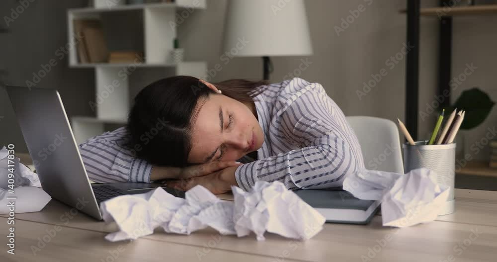 Exhausted millennial bored lazy overworked businesswoman falling asleep on table with computer and crumpled sheets of paper, feeling lack of energy after sleepless restless workday at home or office. Exhausted millennial bored lazy overworked businesswoman falling asleep on table with computer and crumpled sheets of paper, feeling lack of energy after sleepless restless workday at home or office.