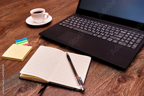 Laptop, notebook with a pen and coffee on the table closeup. Remote work. Distance learning. Online educetion, courses. 
