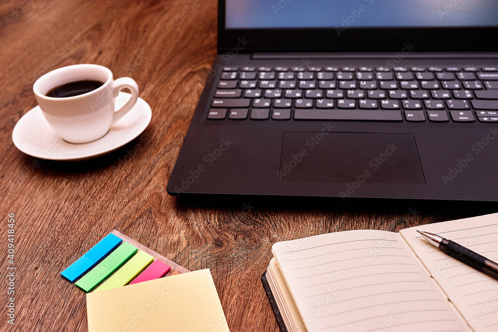 Laptop, notebook and coffee on the table closeup. Remote work. Distance learning. Online educetion, courses. Laptop, notebook and coffee on the table closeup. Remote work. Distance learning. Online educetion, courses.