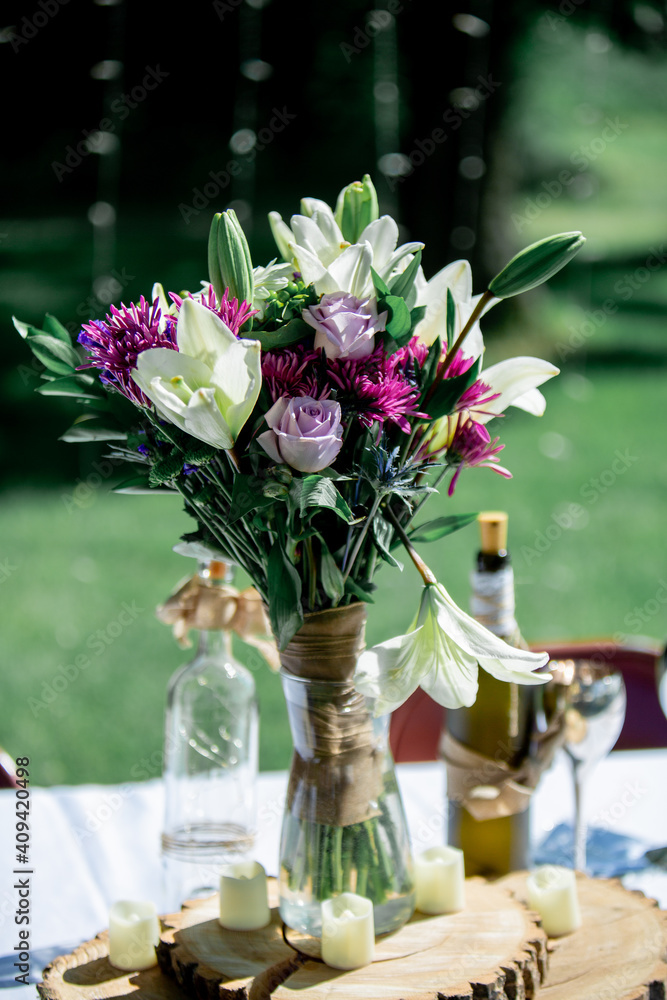 Fresh Yellow, pink, purple flowers in a vase with green leaves and green grass in the background Fresh Yellow, pink, purple flowers in a vase with green leaves and green grass in the background