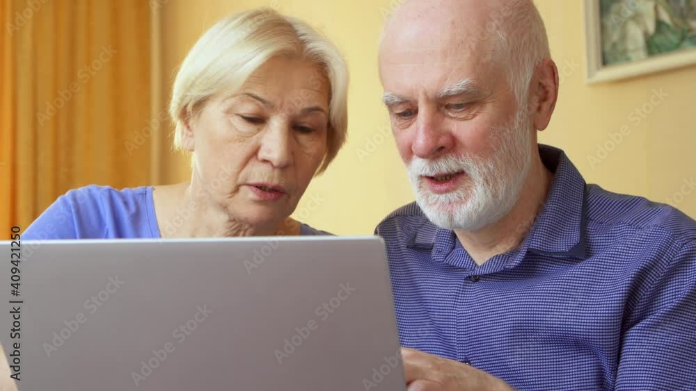 Senior couple at home using laptop. Retired family working on computer learning social media. Computer literacy among elderly people, active modern lifestyle on retirement Senior couple at home using laptop. Retired family working on computer learning social media. Computer literacy among elderly people, active modern lifestyle on retirement