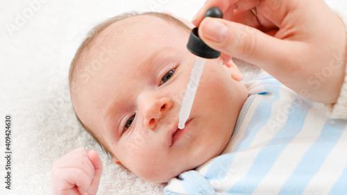 Closeup of giving vaccine from eyedropper or syringe to newborn baby boy