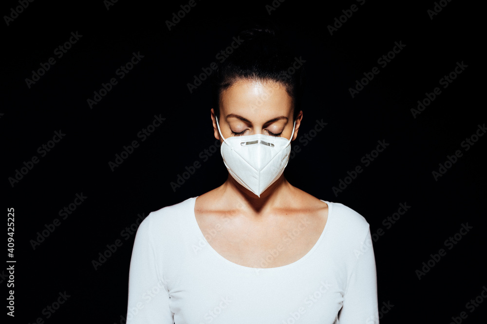 Woman with closed eyes wearing a FFP2 face mask against a black background  Stock Photo | Adobe Stock