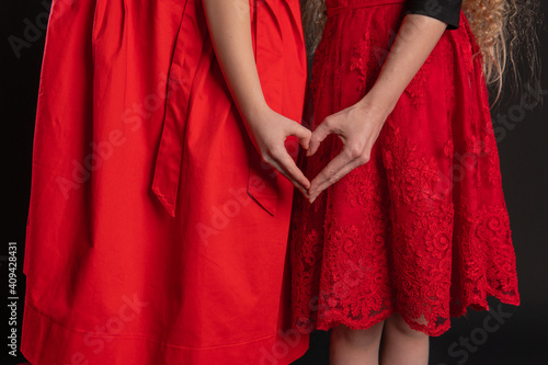 Girl and baby sign of love hands keep the love Valentine's background, the design of valentine, on the floor hearts of romance. February 14 holiday. emotions forever, joy in red girl dress, barefoot