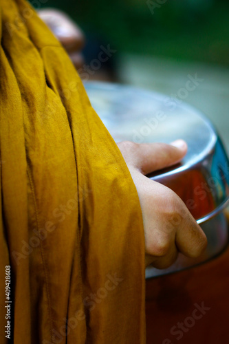 Canvas Print hand of monk dressing orange robe, holding bowl during reception of alms, around