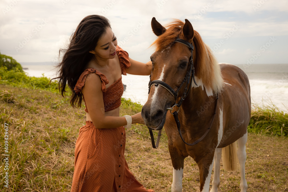 Obraz premium Asian woman cuddling her horse. Horse riding. Human and animals relationship. Nature concept. Bali