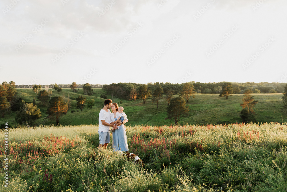Young beautiful family with a little daughter and a dog hug, kiss and walk in nature at sunset. Young beautiful family with a little daughter and a dog hug, kiss and walk in nature at sunset.