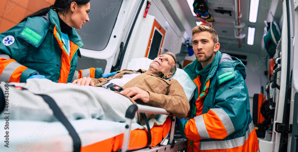 Serious and professional team of doctors in the ambulance moving on a patient into the hospital during an emergency situation. Serious and professional team of doctors in the ambulance moving on a patient into the hospital during an emergency situation.