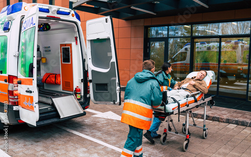 Serious and professional team of doctors in the ambulance moving on a patient into the hospital during an emergency situation.