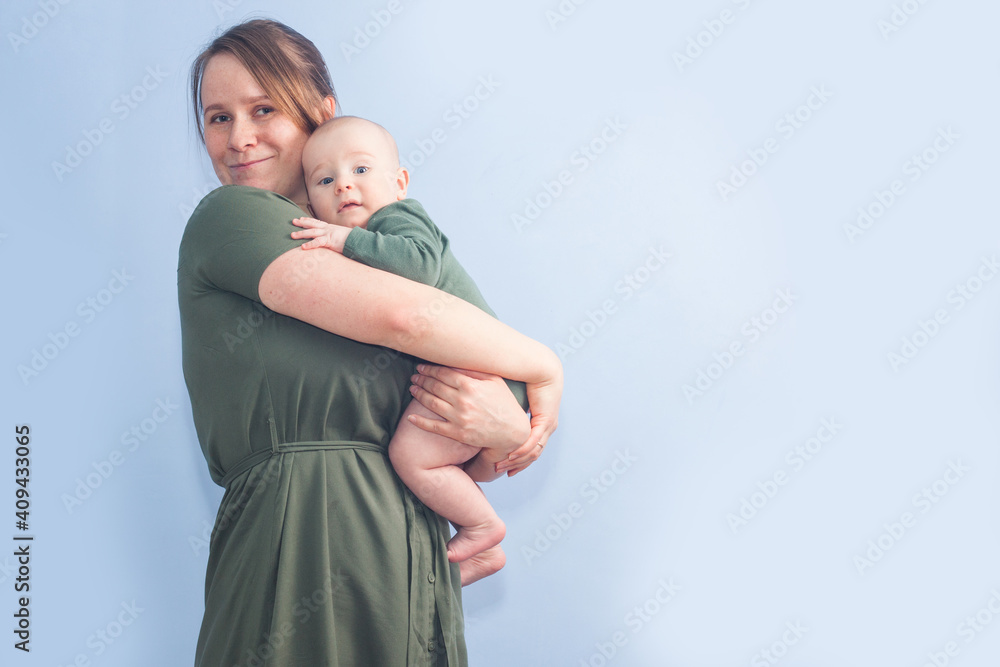 Five month baby in mother's arms on blue background