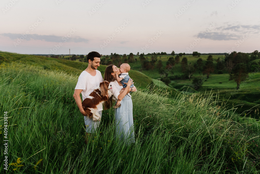 A young beautiful family with a little daughter and a dog hug, kiss and walk in nature. Photo of a family with a small child in nature. A young beautiful family with a little daughter and a dog hug, kiss and walk in nature. Photo of a family with a small child in nature.