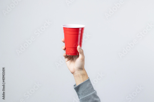 Hand raising the red cup, Copy space.