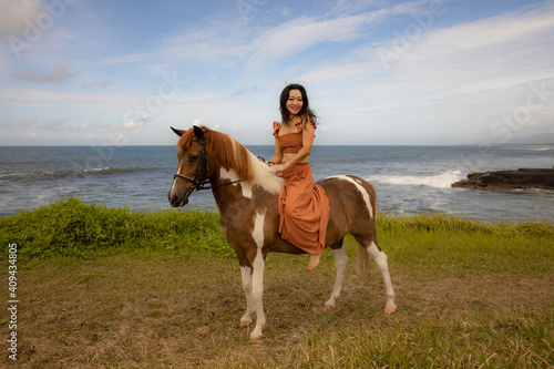 Beautiful woman riding horse near the ocean. Outdoor activities. Traveling concept. Copy space. Bali