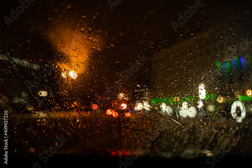 View of the night city through the wet car window with drops
