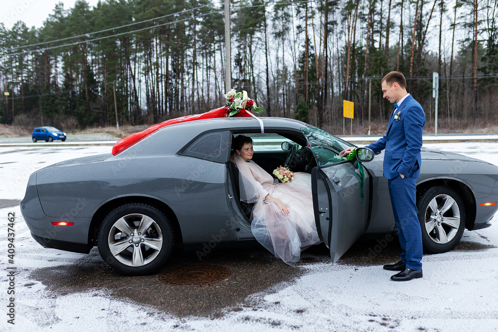 the groom gives his hand to the bride from the car, the politeness and gallantry of people in love, the husband and wife arrived in a decorated car for the wedding the groom gives his hand to the bride from the car, the politeness and gallantry of people in love, the husband and wife arrived in a decorated car for the wedding