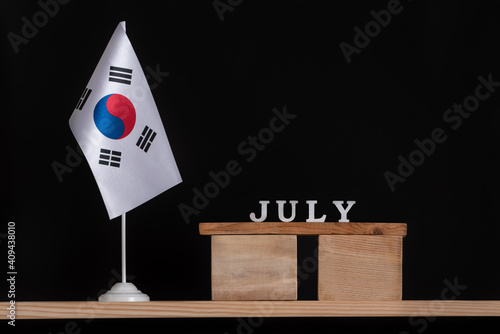 Wooden calendar of July with South Korea flag on black background. Holidays of South Korea in July.