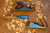 An old wooden jointer and a chisel with shavings lie on the wooden floor. Selective focus. 