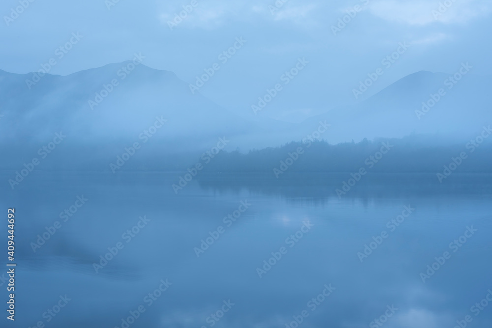 Beautiful landscape image of misty Derwentwater in Lake District on cold Winter morning