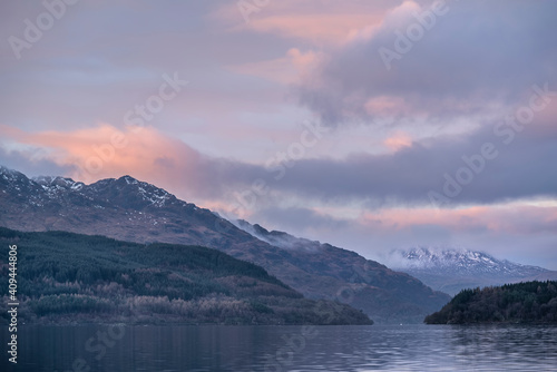Majestic landscape image across Loch Lomond looking towards snow capped Ben Lui mountain peak in Scottish Highlands