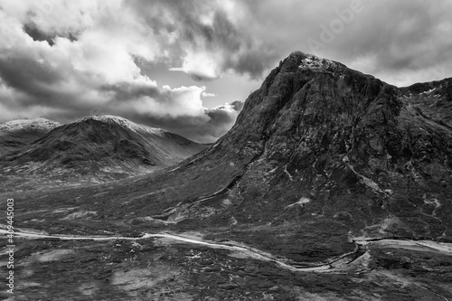 Flying drone epic black and white landscape image of Buachaille Etive Mor and surrounding mountains and valleys in Scottish Highlands on a Winter day
