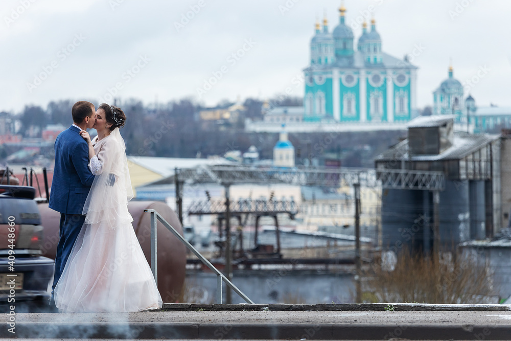 the bride and groom on the background of a church, religious lovers, a wedding walk in winter, a man and a woman gently kiss and smile hugs the bride and groom on the background of a church, religious lovers, a wedding walk in winter, a man and a woman gently kiss and smile hugs