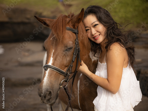 Portrait of smiling woman and brown horse. Asian woman hugging horse. Romantic concept. Love to animals. Nature concept. Bali