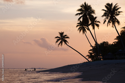 Sunset beach silhouettes against a peach sky.