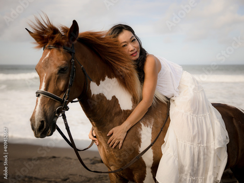 Horsewoman lying on the withers of the horse. Asian woman riding horse on the beach. Homan and animal concept. Bali