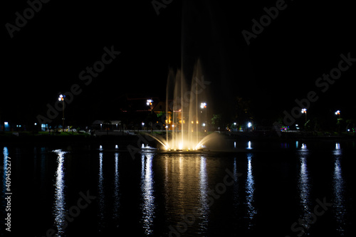 View cityscape Udonthani city and landscape fountain spray in pond night time for thai people travel visit and rest relax at Nong Prajak Recreation Centre Public Park in Udon Thani, Thailand