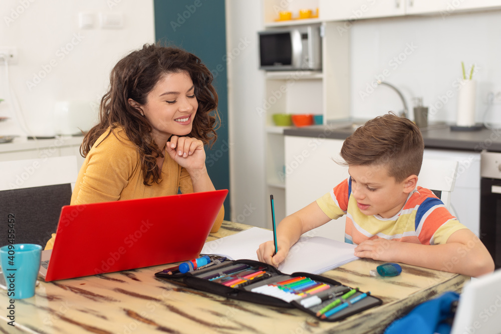 Smiling mother helping adorable son doing schoolwork at home Smiling mother helping adorable son doing schoolwork at home