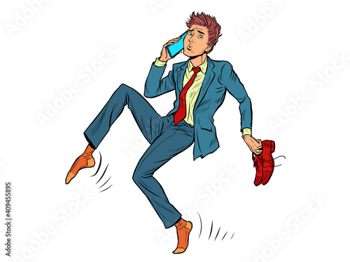 The man sneaks up quietly. Shoes in hand, talking on the phone