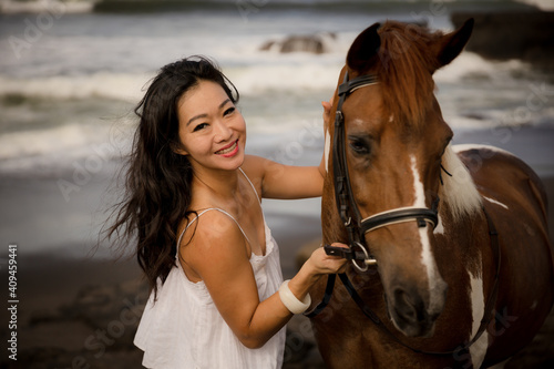 Portrait of smiling woman and brown horse. Asian woman cuddling horse. Romantic concept. Love to animals. Nature concept. Selected focus. Bali