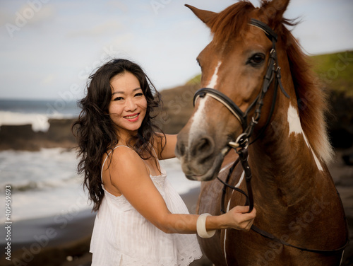 Portrait of smiling woman and brown horse. Asian woman cuddling horse. Romantic concept. Human and animals relationship. Nature concept. Selected focus. Bali