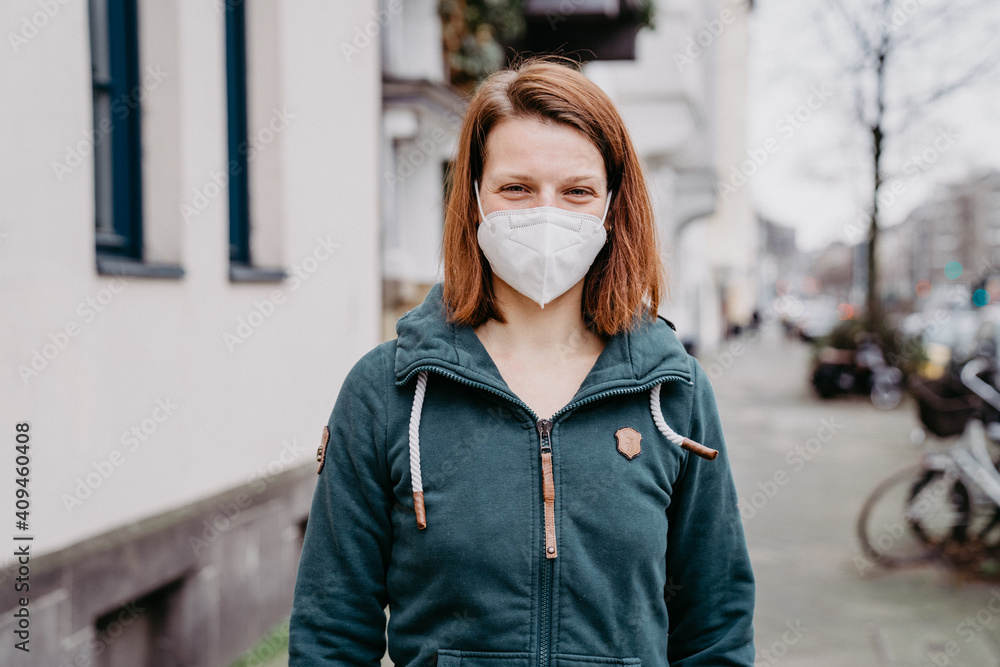 Portrait of happy young woman with thick clothes in winter walking down the street wearing medical mask for protection against corona virus Portrait of happy young woman with thick clothes in winter walking down the street wearing medical mask for protection against corona virus