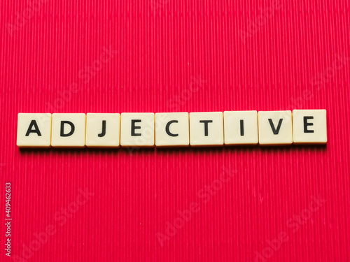 ADJECTIVE word made from square letter tiles on red background. photo