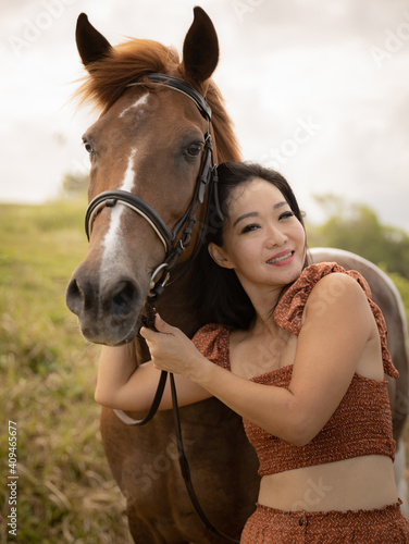 Portrait of happy woman and brown horse. Asian woman hugging horse. Romantic concept. Positive emotions. Human and animals relationship. Nature concept. Bali