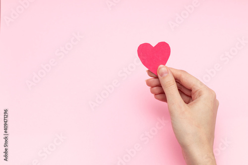 Person holding red heart cards in hands on pink background, top view