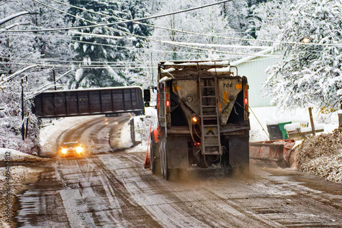 A snow plow truck is heading toward a narrowing of the road as it approaches the train overpass as two cars are heading in opposite direction. Small town of Windsor in Broome County in Upstate NY.