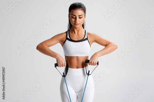 Obraz na płótnie Fitness woman working out with resistance band on gray background