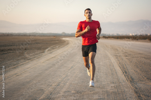 Sporty man jogging on beach and working out in nature