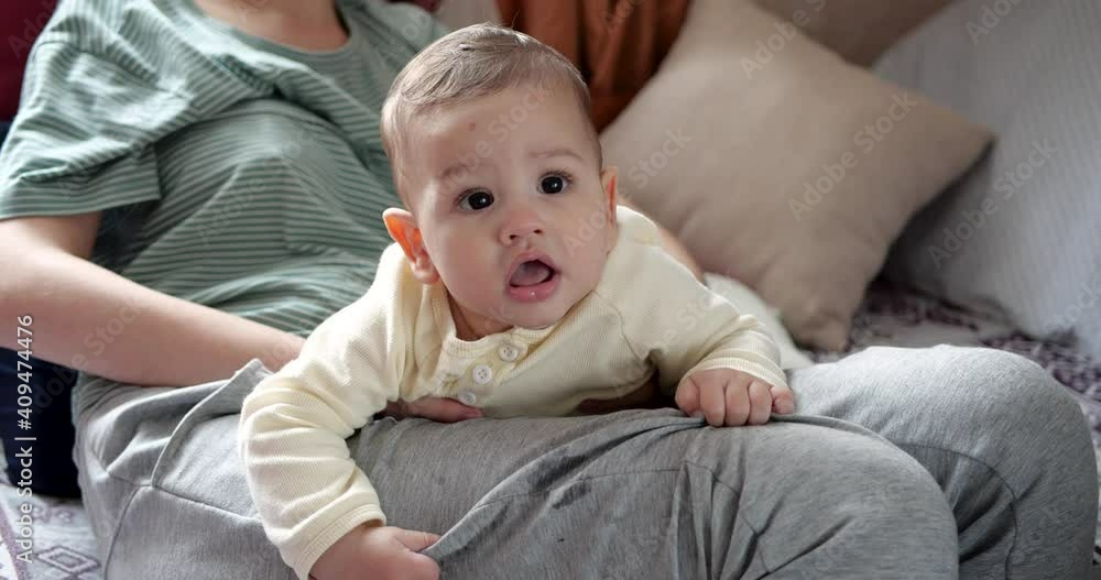 a young mother is holding a beautiful seven-month-old son who smiles and gnaws at fingers and mother's hand. itchy teeth of a newborn, teething a young mother is holding a beautiful seven-month-old son who smiles and gnaws at fingers and mother's hand. itchy teeth of a newborn, teething