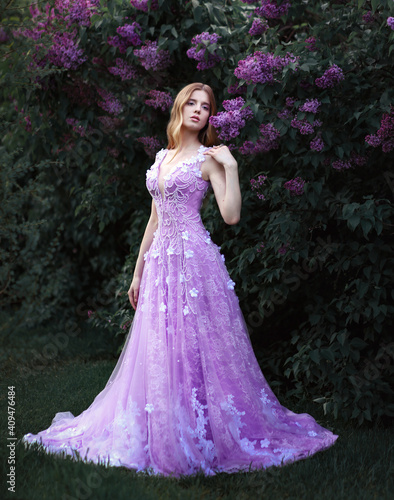 Beautiful blonde girl in violet dress in lilac tree